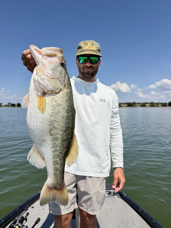 Capt. Jackson Williams holding a trophy largemouth bass on the bow of his bass boat