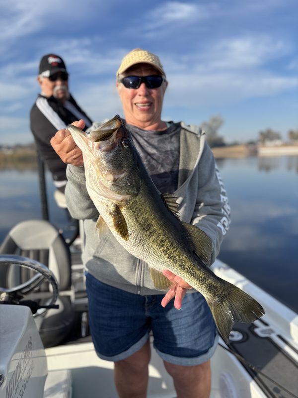 Angler holding a heavy trophy largemouth bass on a guided February charter with the guide behind him